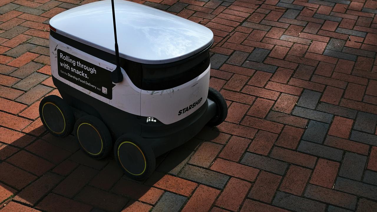 a white and black robot sitting on top of a brick road