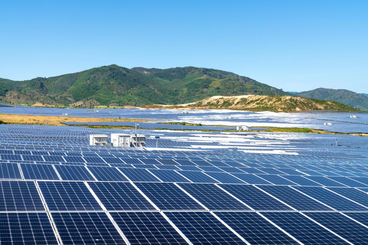 a photo of a solar farm with mountains in the background