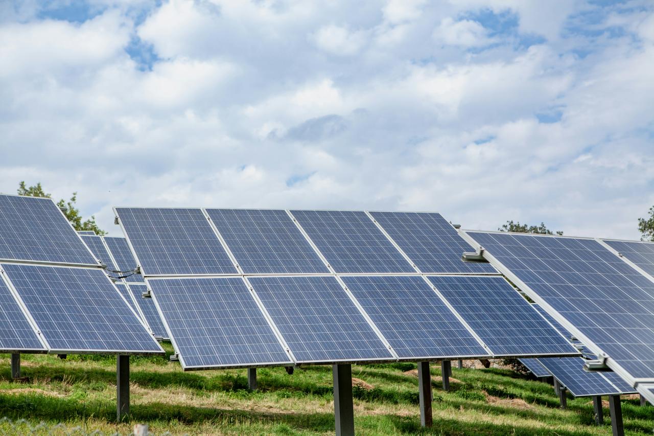 Solar panels in a field under a cloudy sky