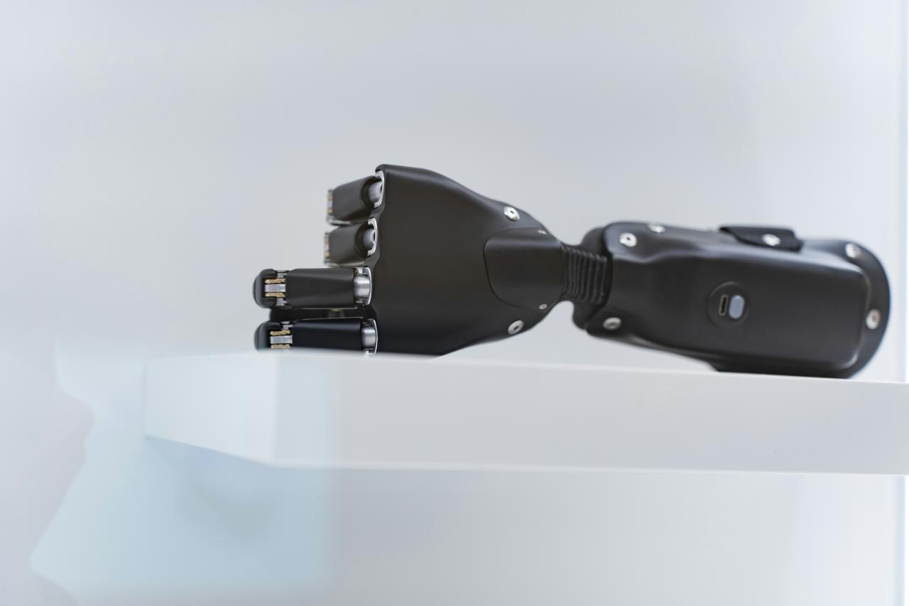 A black prosthetic hand rests on a white shelf.